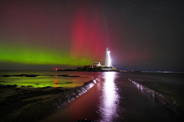 The sky is filled with colour from the aurora borealis, also known as the Northern Lights, at St Mary's lighthouse in Whitley Bay on the North East coast of England on Wednesday, March 26, 2025. (Photo by Owen Humphreys/PA Wire)