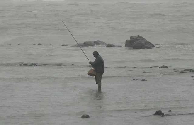 An Indian angler fishes on the sea front during heavy rain showers in Mumbai on June 18, 2013. The monsoon, which India's farming sector depends on, covers the subcontinent from June to September, usually bringing some flooding. But the heavy rains arrived early this year, catching many by surprise. The country has received 68 percent more rain than normal for this time of year, data from the India Meteorological Department shows. (Photo by Punit Paranjpe/AFP Photo)