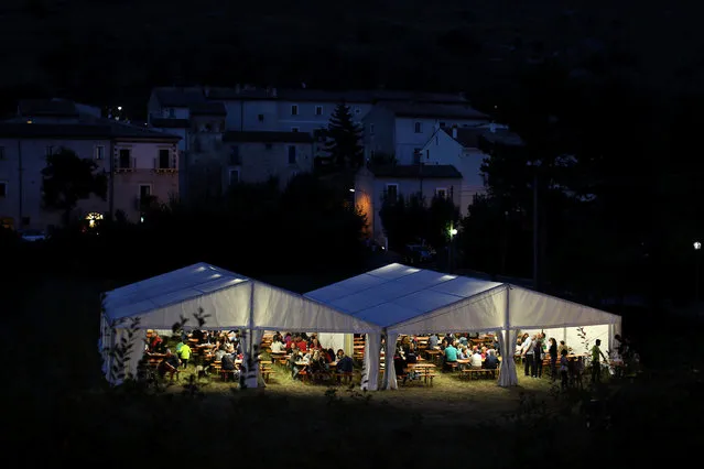 People eat underneath a temporary tent during a fair organised every year to attempt to boost the economy of the town of Santo Stefano di Sessanio in the province of L'Aquila in Abruzzo, inside the national park of the Gran Sasso e Monti della Laga, Italy, September 3, 2016. (Photo by Siegfried Modola/Reuters)