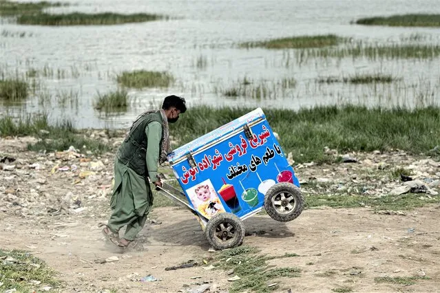 An Afghan ice cream vendor pushes his cart as he looks for customers near the Shuhada Lake in Kabul on May 2, 2023. (Photo by Wakil Kohsar/AFP Photo)