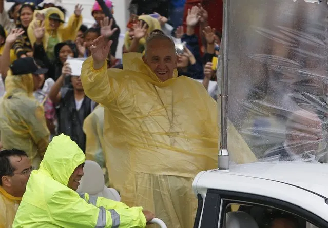 Pope Francis smiles as he waves to residents during a motorcade in Tacloban city, after holding a mass near the airport, January 17, 2015. An emotional Francis, wearing a plastic poncho over his vestments to protect him from the wind and rain on Saturday, comforted survivors of Typhoon Haiyan, the Philippines' worst natural disaster that killed about 6,300 people 14 months ago. (Photo by Erik De Castro/Reuters)