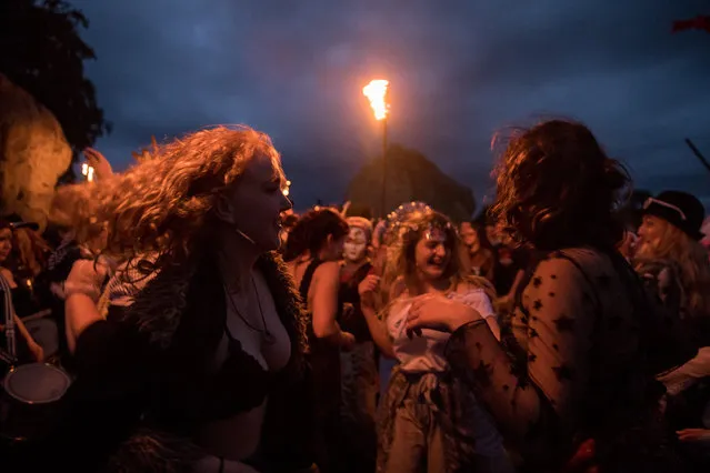 People dance as they gather at Avebury Neolithic henge monument, a UNESCO World Heritage site, after the sun has set, on June 20, 2018 in Wiltshire, England. Constructed in the Third Millennium BC, the Neolithic monument, one of the best known prehistoric sites in Britain, contains the largest megalithic stone circle in the world. Hundreds of druids, pagans and revellers gathered at the ancient monument, which forms part of the wider prehistoric landscape of Wiltshire and includes nearby Stonehenge, to watch the sunset and the sunrise, marking the northern hemisphere's summer solstice. (Photo by Matt Cardy/Getty Images)