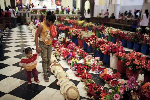 Girls look at offerings left by devotees to celebrate the Day of the Virgin of Guadalupe inside the Basilica of Guadalupe in San Salvador, El Salvador December 11, 2015. (Photo by Jose Cabezas/Reuters)