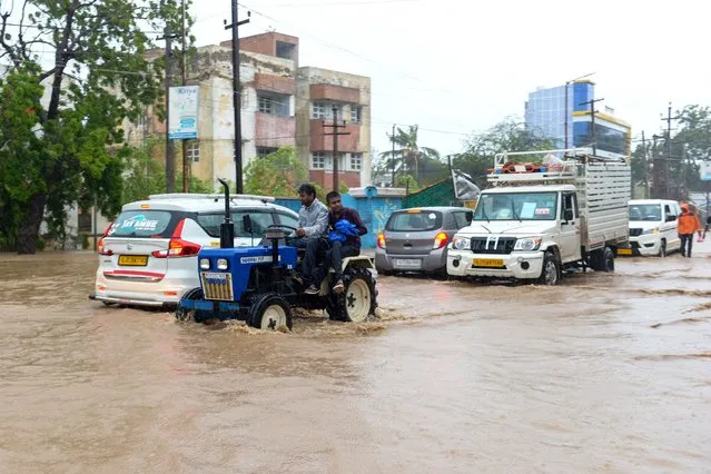 Motorists traverse through floodwaters in Mandvi town, some 100km southeast of Jakhau Port, on June 16, 2023, after cyclone Biparjoy made landfall. Cyclone Biparjoy tore down power poles and uprooted trees on June 16 after pummelling the Indian coastline, though the storm was weaker than feared and there were no immediate reports of casualties. (Photo by Sam Panthaky/AFP Photo)