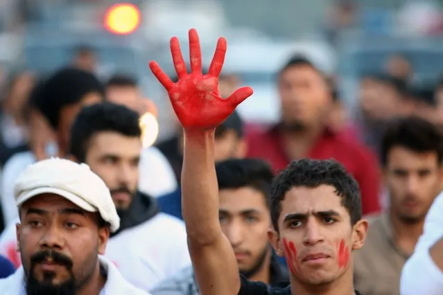 An Iraqi man displays his hand, painted red to symbolize blood, during a demonstration against the ongoing violence and lack of security in the southern city of Basra on December 17, 2015. (Photo by Haidar Mohammed Ali/AFP Photo)