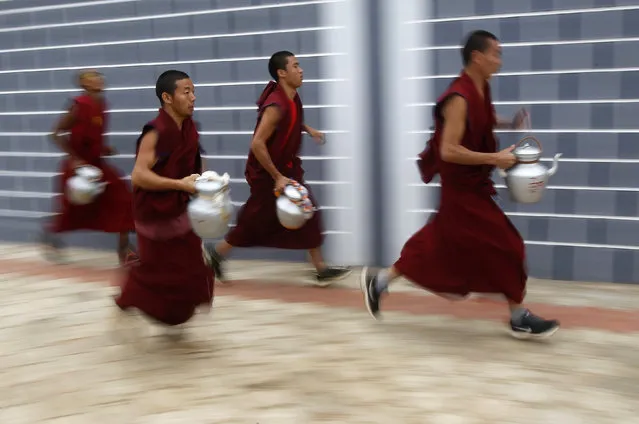Buddhist monks carrying kettles run towards the monastery to serve tea to attendees of the Jangchup Lamrim teachings conducted by the Tibetan spiritual leader the Dalai Lama (unseen) at the Tashi Lhunpo Monastery in Bylakuppe in the southern state of Karnataka, India, December 21, 2015. (Photo by Abhishek N. Chinnappa/Reuters)