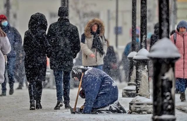 An old woman begs on the street during snowfall in Moscow, Russia, 21 February 2021. The temperature in the Russian capital dro​pped to minus 13 degrees Celsius. (Photo by Yuri Kochetkov/EPA/EFE)