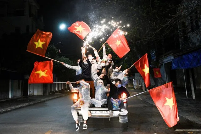 Residents come out to celebrate with national flags and fireworks after Hai Duong authorities end 34 days of social distancing amid the spread of the coronavirus disease (COVID-19) in Chi Linh city, Hai Duong province, Vietnam, March 3, 2021. (Photo by Thanh Hue/Reuters)