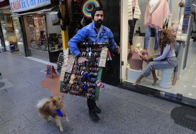 Ibrahim Farshoukh, 28, owner of a leather bracelets and bags shop, carries a stand with his products, on Beirut's commercial Hamra Street, in Beirut, Lebanon, Tuesday, March 16, 2021. More than half the population now lives in poverty, while an intractable political crisis heralds further collapse and Lebanese are gripped by fear for the future. (Photo by Hussein Malla/AP Photo)