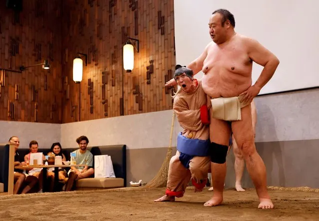 Nadine, a 43-year-old tourist from the U.S., wearing a sumo wrestler costume, tries to spar against former sumo wrestler Towanoyama on the sumo ring before tourists from abroad, at Yokozuna Tonkatsu Dosukoi Tanaka in Tokyo, Japan on June 30, 2023. (Photo by Issei Kato/Reuters)