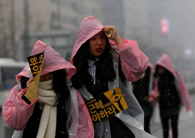 A protester wears a placard as she makes her way to join a protest calling for South Korean President Park Geun-hye to step down, as it snows in Seoul, South Korea, November 26, 2016. The placard reads, “President Park Geun-hye, step down”. (Photo by Kim Kyung-Hoon/Reuters)