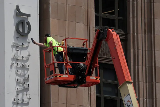 A worker uses a smartphone while dismantling a Twitter's sign at Twitter's corporate headquarters building as Elon Musk renamed Twitter as X and unveiled a new logo, in downtown San Francisco, California, U.S., July 24, 2023. (Photo by Carlos Barria/Reuters)