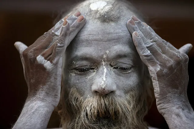 A Naga Sadhu or Naked Hindu holy man rubes ash as he prepares to take holy dips in the river Ganges during Shahi snan or a Royal bath during Kumbh mela, in Haridwar in the Indian state of Uttarakhand, Monday, April 12, 2021. As states across India are declaring some version of a lockdown to battle rising Covid cases as part of a nationwide second-wave, thousands of pilgrims are gathering on the banks of the river Ganga for the Hindu festival Kumbh Mela. The faithful believe that a dip in the waters of the Ganga will absolve them of their sins and deliver them from the cycle of birth and death. (Photo by Karma Sonam/AP Photo)