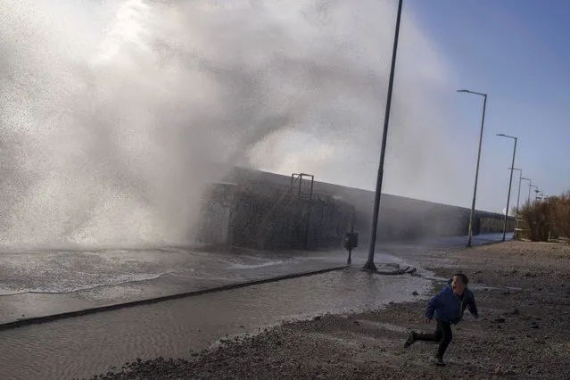 Waves crash on a sea wall as a boy runs during a windy day in the southern Athens coastal suburb of Flisvos, Greece, Thursday, January 19, 2023. (Photo by Petros Giannakouris/AP Photo)