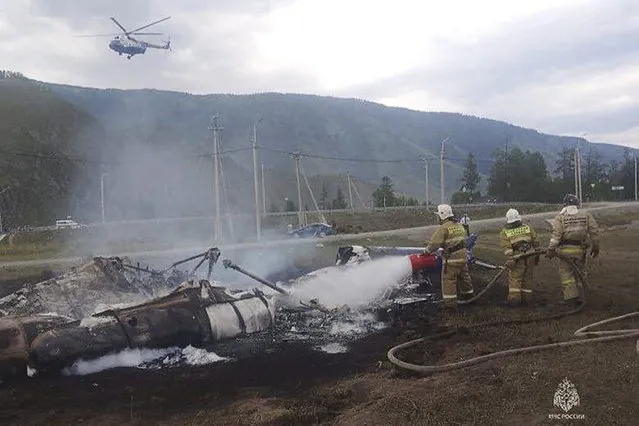 In this image provided by Russian Emergency Situations Ministry press service, firefighters extinguish a Mi-8 helicopter after the crash near Tyungur village, Altai Republic in southern Siberia, Russia, Thursday, July 27, 2023. A helicopter crashed in Russia's Siberia on Thursday, killing six of those on board and injuring seven, Russian emergency officials reported. (Photo by Ministry of Emergency Situations press service via AP Photo)
