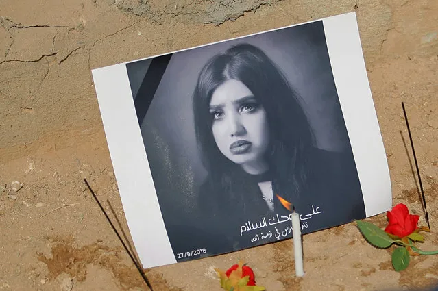In this Monday, October 1, 2018 photo, fans of slain former beauty queen, fashion model and social media star Tara Fares left flowers and  candles at her gravesite, in Najaf, Iraq. Fares won fame in conservative, Muslim-majority Iraq with outspoken opinions on personal freedom. Last week, she was shot and killed at the wheel of her white Porsche on a busy Baghdad street. The violence reverberated across Iraq and follows the slaying of a female activist in the southern city of Basra and the mysterious deaths of two well-known beauty experts. (Photo by Anmar Khalil/AP Photo)