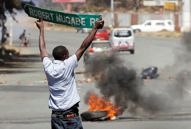 A man carries a street sign as opposition party supporters clash with police in Harare, Zimbabwe, August 26, 2016. (Photo by Philimon Bulawayo/Reuters)