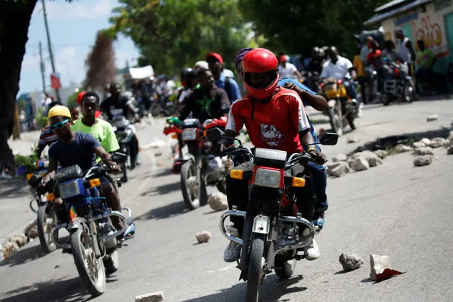 Protesters ride their motorbikes along a street blocked by rocks during a march to demand an investigation into what they say is the alleged misuse of Venezuela-sponsored PetroCaribe funds, in Port-au-Prince, Haiti on October 17, 2018. (Photo by Andres Martinez Casares/Reuters)