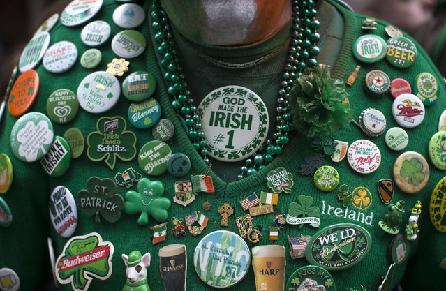 A man wears a sweater covered in Irish themed pins as he stands with thousands of spectators to watch the 254th New York City St. Patrick's Day parade up 5th Avenue in the Manhattan Borough of New York, March 17, 2015. (Photo by Mike Segar/Reuters)
