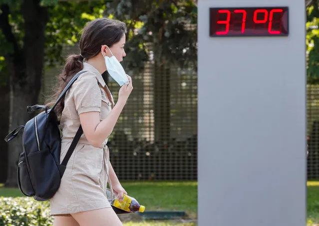 Russian woman walks in front of informational panel shows temperature 37 degrees Celsius in Moscow, Russia, 23 June 2021. The temperature exceeded 37 degrees Celsius in Moscow. (Photo by Yuri Kochetkov/EPA/EFE)