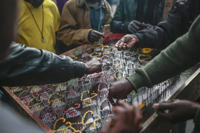 Sub-Saharan migrants compete at a table game as a way to make money, at Ouled Ziane camp in Casablanca, Morocco, Thursday, December 6, 2018. As Morocco prepares to host the signing of a landmark global migration agreement next week, hundreds of migrants are languishing in a Casablanca camp rife with hunger, misery and unsanitary conditions. These sub-Saharan Africans who dream of going to Europe are a symbol of the problems world dignitaries are trying to address with the U.N.'s first migration compact. (Photo by Mosa'ab Elshamy/AP Photo)