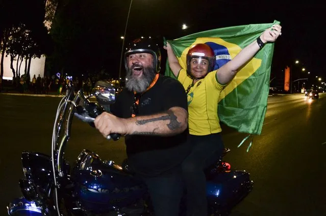 Supporter of Brazilian President Jair Bolsonaro, who is running for another term, ride a motorcycle after the general election polls closed in Brasilia, Brazil, Sunday, October 2, 2022. (Photo by Ton Molina/AP Photo)
