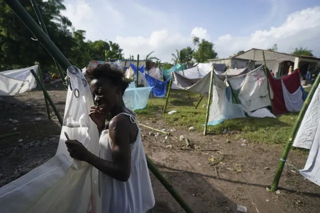 A woman displaced by the 7.2 magnitude earthquake flosses her teeth amid improvised tents set up by displaced residents next to a school, in Les Cayes, Haiti, Wednesday, August 18, 2021. (Photo by Fernando Llano/AP Photo)