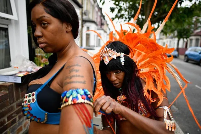 A reveller helps a woman prepare her costume after the normal Notting Hill Carnival festivities were cancelled for a second year running, amid the coronavirus disease (COVID-19) outbreak, in London, Britain, August 30, 2021. (Photo by Beresford Hodge/Reuters)