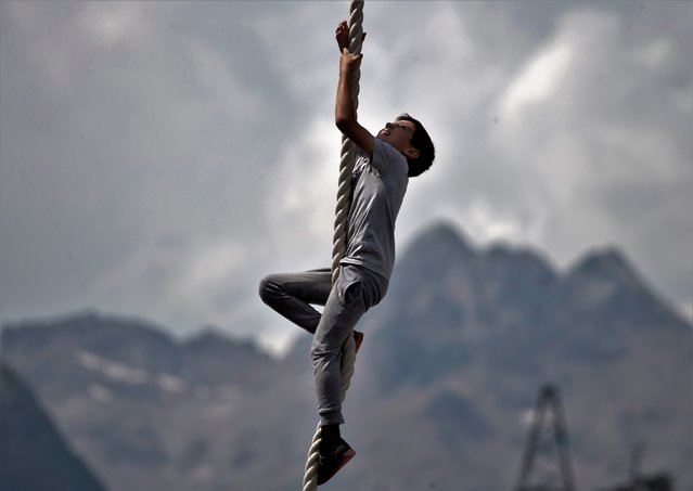 A local boy climbs a rope during the Festival of World Records held in Prielbrusye (Mount Elbrus area) at a height of 2,000m above sea level to mark the upcoming Statehood Day of Kabardino-Balkaria, Russia on August 23, 2021. (Photo by Yelena Afonina/TASS)