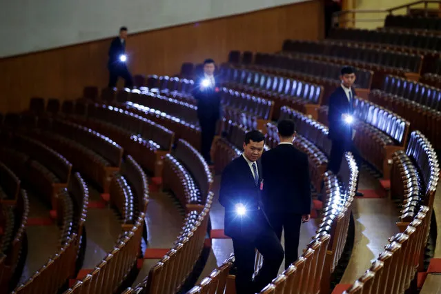 Security personnel check the seats with torches at the end of the opening session of the National People's Congress (NPC) at the Great Hall of the People in Beijing, China, March 5, 2019. (Photo by Jason Lee/Reuters)
