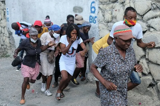 People who were marching to the prime ministers' residence, to demand justice for the assassination of Haitian President Jovenel Moise, run from tear gas fired by police in Port-au-Prince, Haiti, Wednesday, October 20, 2021. (Photo by Matias Delacroix/AP Photo)