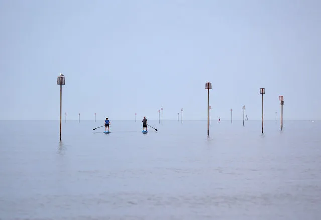 Paddleboarders on a very calm sea around these sea defence groyne markers at Heacham, Norfolk, on September 16, 2021. (Photo by Paul Marriott/Rex Features/Shutterstock)