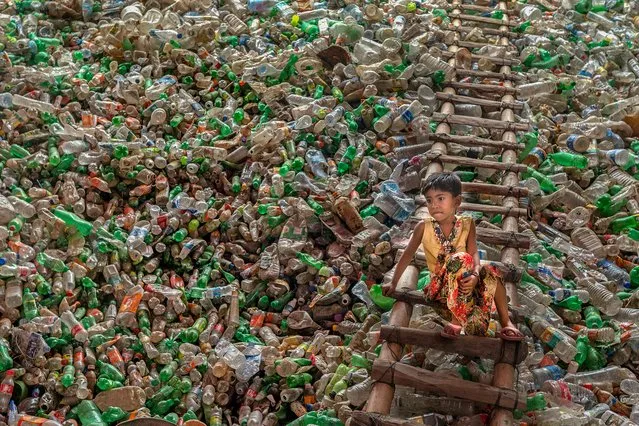 Shortlisted: Confined in Plastic, Chittagong, Bangladesh, 2021. A child sits on a ladder in a plastic bottle recycling factory in Bangladesh. PET recycling in Bangladesh is a growing industry, however collection and sorting are predominantly done by hand. (Photo by Subrata Dey/CIWEM Environmental Photographer of the Year 2021)
