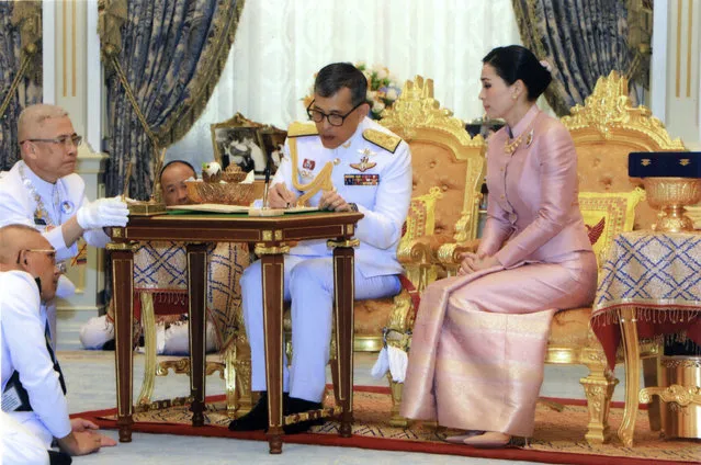 In this photo released by Bureau of the Royal Household ,Thailand's King Maha Vajiralongkorn Bodindradebayavarangkun, center, sits with Queen Suthida Vajiralongkorn Na Ayudhya as they sign their marriage certificates at Ampornsan Throne Hall in Bangkok, Thailand, Wednesday, May 1, 2019. (Photo by Bureau of the Royal Household via AP Photo)
