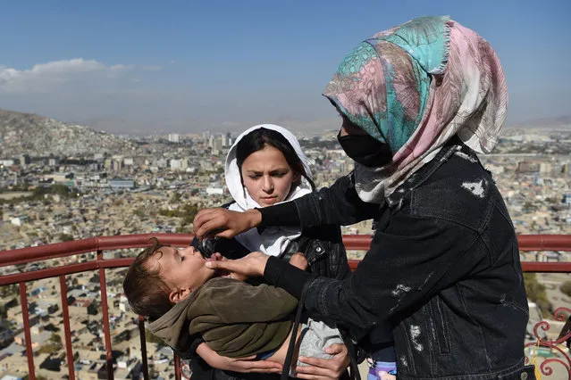 A health worker administers polio vaccine drops to a child during a vaccination campaign in the old quarters of Kabul on November 8, 2021. (Photo by Wakil Kohsar/AFP Photo)