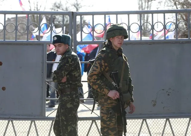 A Ukrainian serviceman (L) stands next to an armed man, believed to be a Russian soldier, inside a Ukrainian military base in the Crimean town of Yevpatoria, March 5, 2014. The United States and Britain failed in an attempt to bring Russia and Ukraine together on Wednesday at a meeting in Paris of a group created to assure Kiev's security after it renounced nuclear weapons in the 1990s. (Photo by David Mdzinarishvili/Reuters)