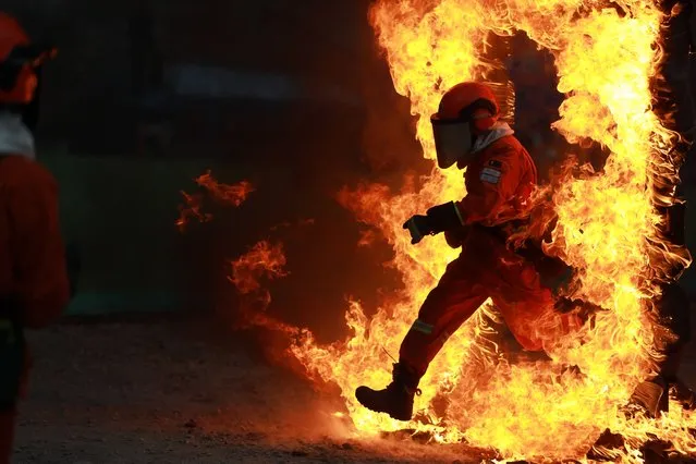 A firefighter passes through fire in a firefighting drill on December 7, 2021 in Aba Tibetan and Qiang Autonomous Prefecture, Sichuan Province of China. (Photo by Zeng Peng/VCG via Getty Images)