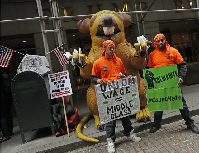 Nicholas Taveras Jr., left, and Anthony Lebron, both of Local 1, the Bricklayers and Allied Craft Workers Union, stand in front of an inflatable rat outside 40 Wall Street, a Trump-owned property, during a May Day rally, Wednesday, May 1, 2019, in New York. (Photo by Kathy Willens/AP Photo)