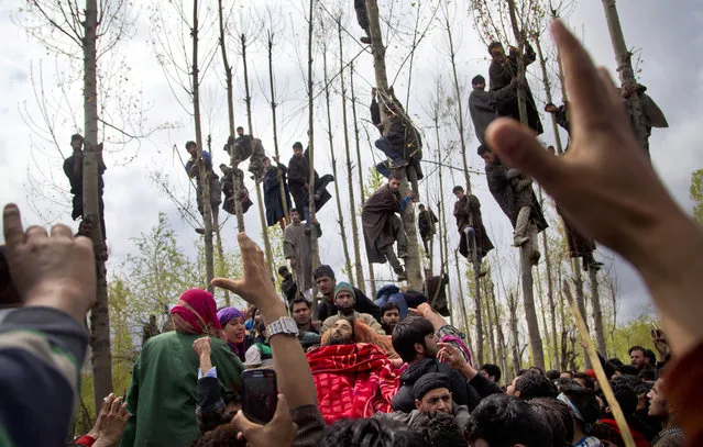 Kashmiri Muslims try to get the glimpse of the body of Waseem Malla, a suspected militant of Hizbul Mujahideen, during his funeral procession in Pehlipora, some 60 kilometers (35 miles) south of Srinagar, Indian controlled Kashmir, Thursday, April 7, 2016. Anti-India protesters attacked government forces with rocks and burned an armored vehicle Thursday as they participated in the funerals of two insurgents killed in a gunbattle in the disputed Kashmir region, an Indian official said. (Photo by Dar Yasin/AP Photo)