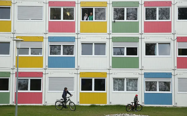 Children play as residents look from their window at the container settlement shelter for refugees and migrants in Zehlendorf district on April 14, 2016 in Berlin, Germany. Locals, many of them retirees, come to the shelter regularly to help the refugees and migrants, who are from countries including Syria, Iraq, Afghanistan, Kosovo and Serbia. The coalition partners of the German government yesterday announced a new package of legislation that includes measures to foster the integration of refugees who have received asylum status in Germany. (Photo by Sean Gallup/Getty Images)