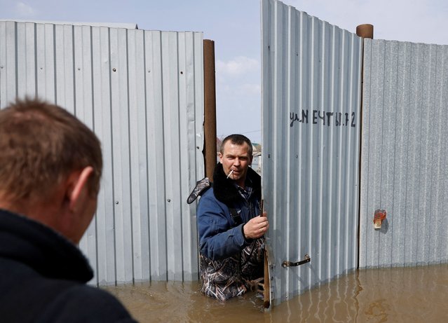 Local resident Dmitry Dragoshantsev smokes as he stands in the gate of a flooded house in Orenburg, Russia, on April 12, 2024. The sign on the gate reads: “Dream Street”. (Photo by Maxim Shemetov/Reuters)