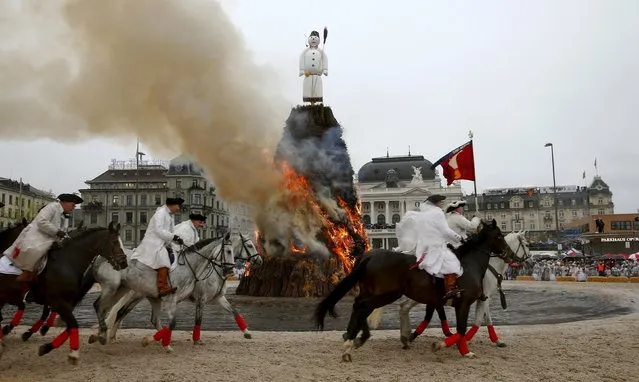 Mounted guildsmen gallop around the Boeoegg, a snowman made of wadding and filled with firecrackers, as it burns atop a bonfire in the Sechselaeuten square in Zurich, Switzerland, April 18, 2016. As the bells of St. Peter's church chime six o'clock, the bonfire below the “Boeoegg” is set alight and mounted guildsmen gallop around the pyre to the tune of the Sechselaeuten March. The faster the head of the “Boeoegg”, the symbol of winter, catches fire and explodes, the warmer and more beautiful the summer will be. (Photo by Arnd Wiegmann/Reuters)