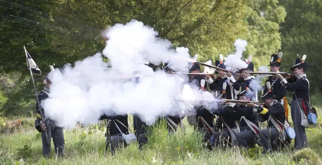 In this May 10, 2015, photo, historical re-enactors dressed as soldiers of the Belgian-Dutch 7th Battalion of the Line fire their weapons during a drill at a Napoleonic era living history camp in Elewijt, Belgium. The Belgian-Dutch living history group is coordinating their group for participation in the 200th anniversary of the Battle of Waterloo which will take place in June 2015. (AP Photo/Virginia Mayo)