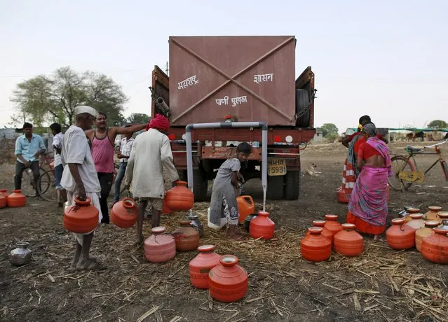 People fill their containers with water from water at a village in Osmanabad, India, April 15, 2016. (Photo by Danish Siddiqui/Reuters)