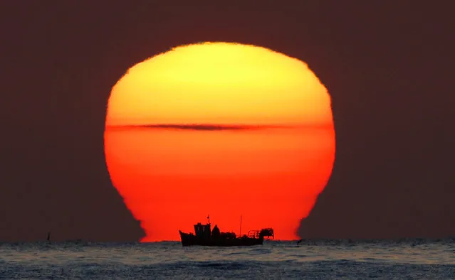 A lobster fisherman checks his pots as the sun rises over his small fishing boat in the North Sea near Whitley Bay in Northumberland, England on April 20, 2016. (Photo: Owen Humphreys/PA Wire/ZUMA Press)