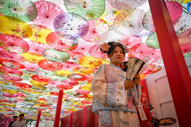A woman dressed in traditional clothing visits a business street in Beijing on June 5, 2024. (Photo by Wang Zhao/AFP Photo)