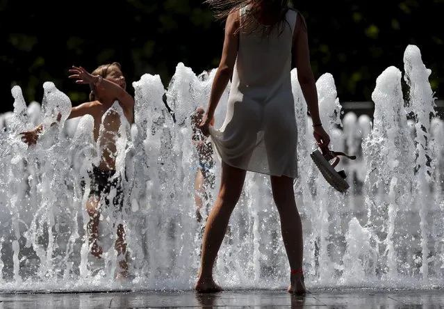 A young woman cools herself in a fountain in Budapest, Hungary July 6, 2015. (Photo by Laszlo Balogh/Reuters)