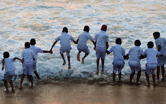 Sri Lankan schoolchildren play at the water' s edge on a beach during sunset in Colombo on February 8, 2017. (Photo by Lakruwan Wanniarachchi/AFP Photo)