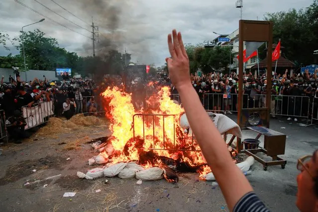 Protesters show the three-finger salute as they burn mock body bags, representing casualties of coronavirus disease (COVID-19), during an anti-government demonstration, in Bangkok, Thailand on July 18, 2021. (Photo by Soe Zeya Tun/Reuters)
