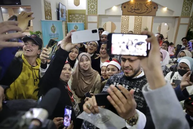 Al-Zahraa Layek Helmee, center, is surrounded by her fans for selfie pictures at the annual Cairo International Book Fair, in Cairo, Egypt, February 4, 2022. Online, where Helmee has 1.2 million followers on Facebook, many cheer her on. Others – men and women – reprimand her in messages, urging her to “fear God” or arguing that her voice can tempt men, an idea she rejects. (AP Photo/Amr Nabil)